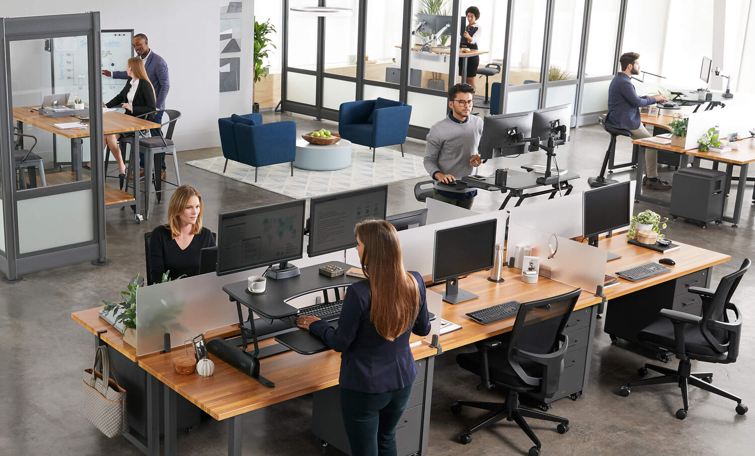 open office with several professionals at work, some in benched seating, others in private offices, and other having casual meetings, all with Vari furniture