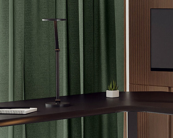Close up view of the edge of the l shape electric standing desk with a pen and paper on desk