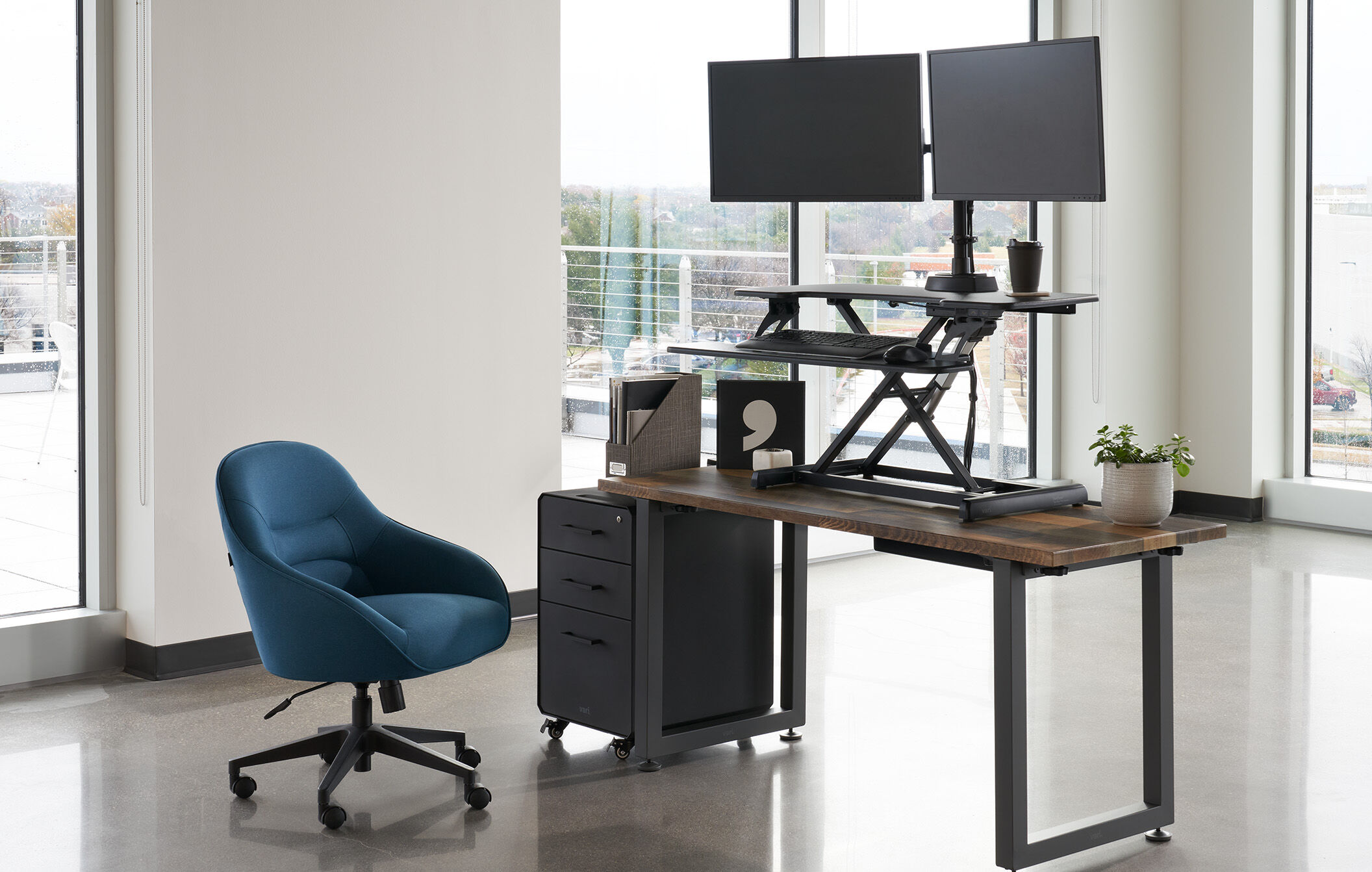 workspace setup with a converter on top of a table, a file cabinet and a desk chair  image