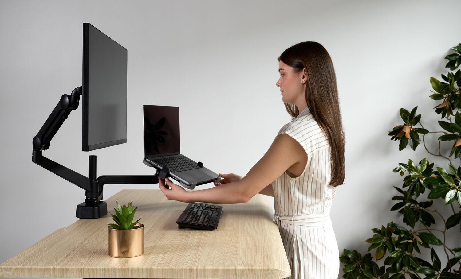 woman adjusting the laptop holder that has been installed on a desk