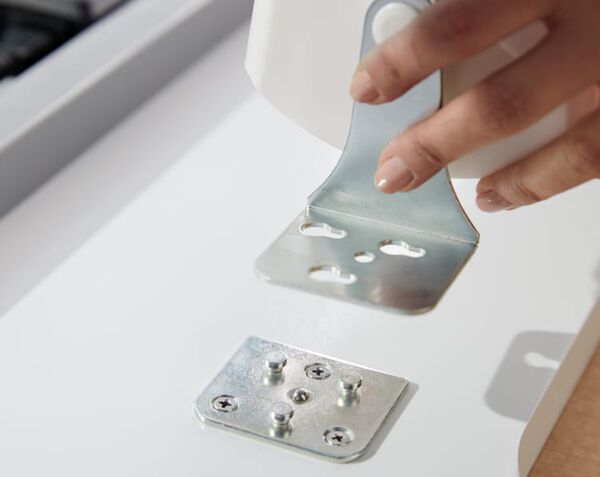 View of individual setting up a cable management tray under a desktop