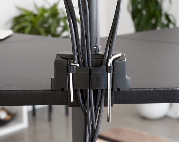 Close up view of monitor arm attached to desk in office being adjusted