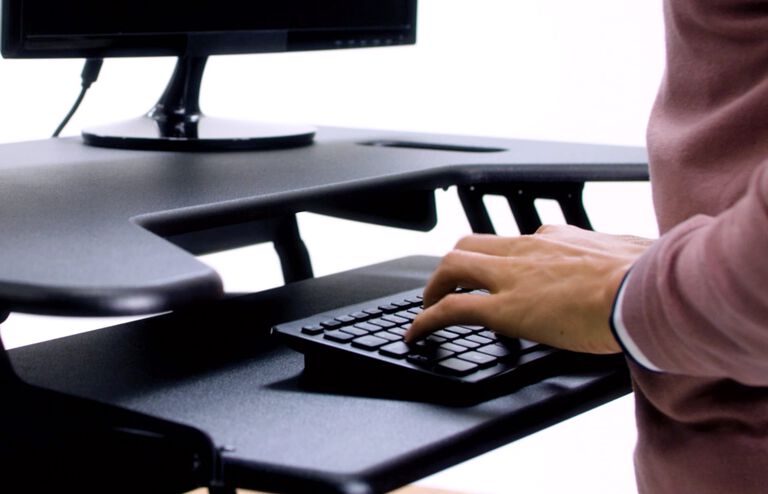 Individuals adjusting VariDesk Cube Plus 40 to seated position