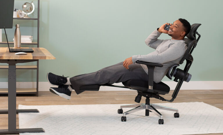 Professional working from home in the vari comfortflex office chair leaning back comfortably while talking on the phone