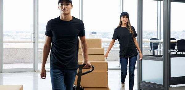two workers delivering vari office furniture in boxes on a pull cart demonstrating simplicity