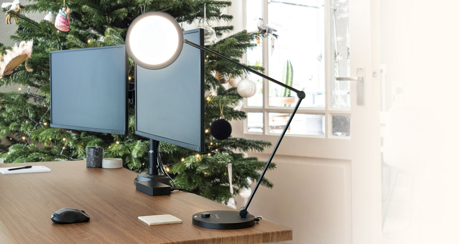 a lamp on top of a desk with a christmas tree behind that desk