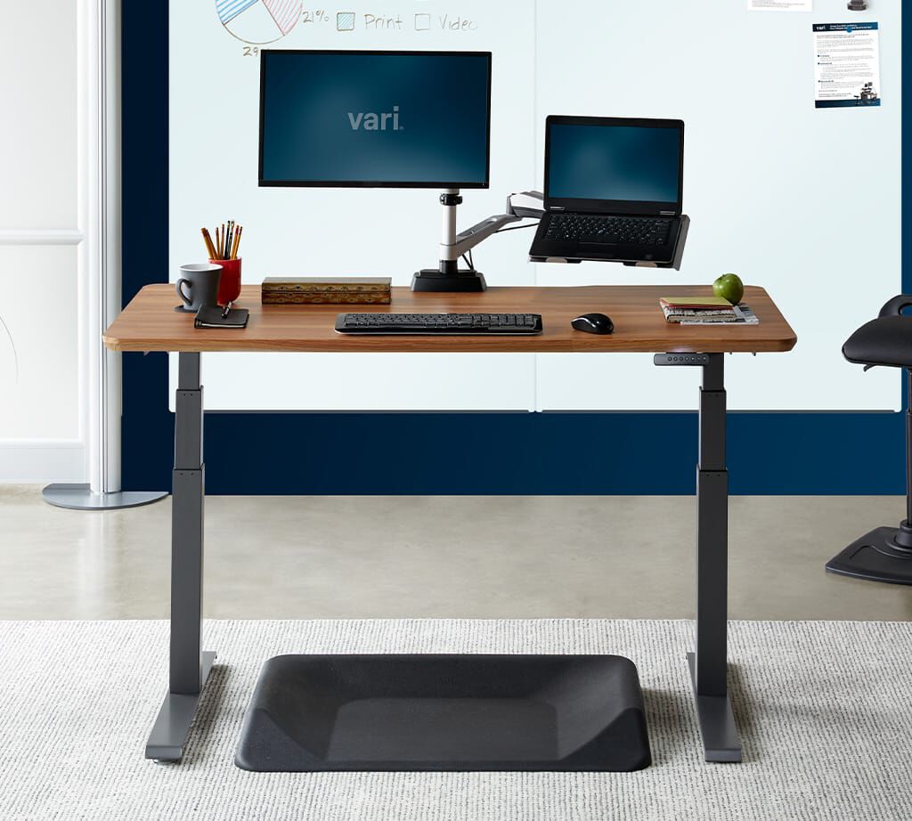 Electric Standing Desk with one monitor and laptop raised in office