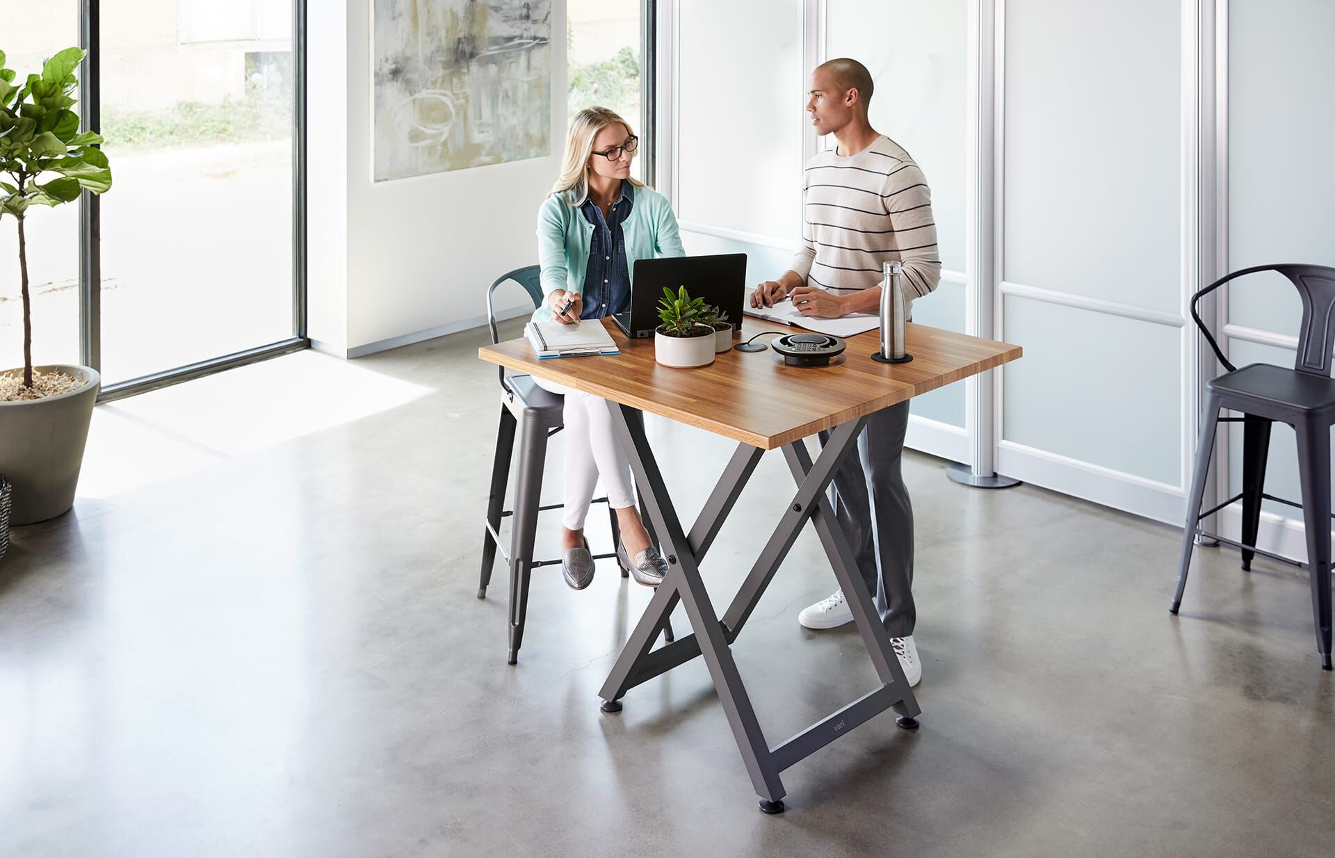 Two professionals hold a casual meeting at the Standing Meeting Table