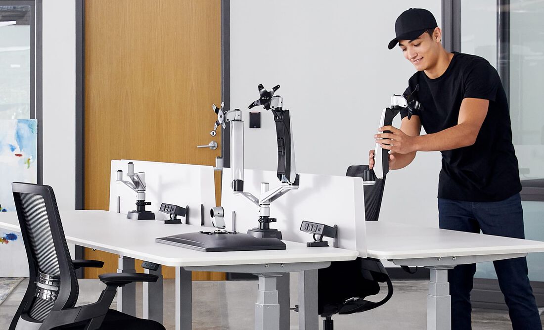 Person installing one two monitor arms in office space