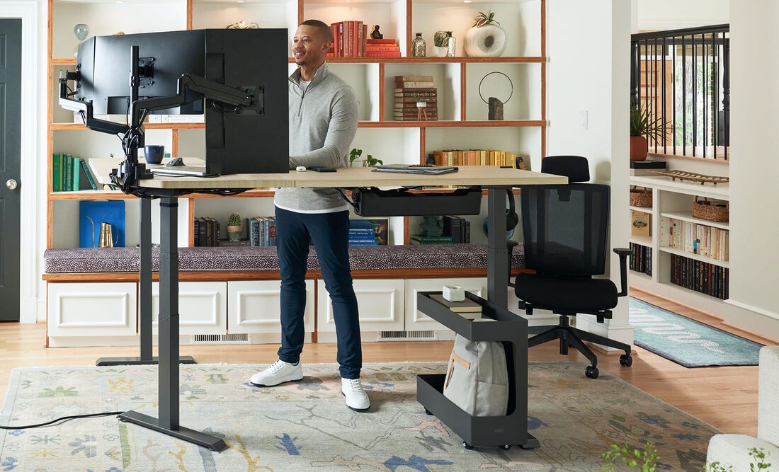 individual standing a working at a electric standing desk in their home office