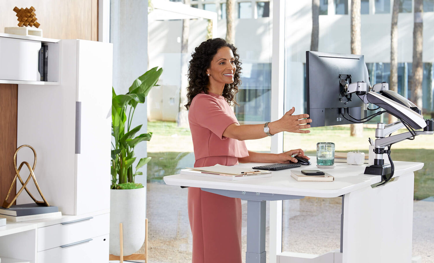 professional adjusting monitors on their electric standing desk with executive collection products