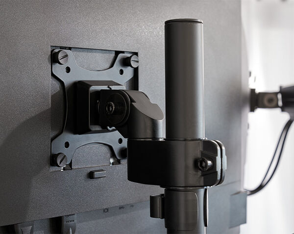 Close up view of monitor arms attached to desk in office
