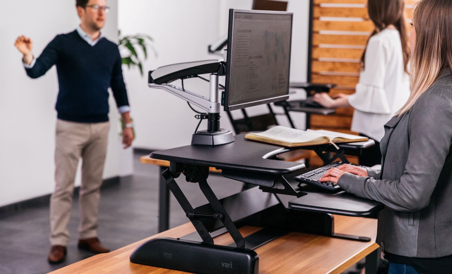 professor lectures to class of students who are standing while working on their computers, each at a VariDesk desktop converter