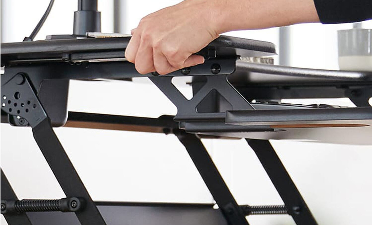 Desk converter lowered to sitting position with a sinle monitor arm mounted on it in an office setting