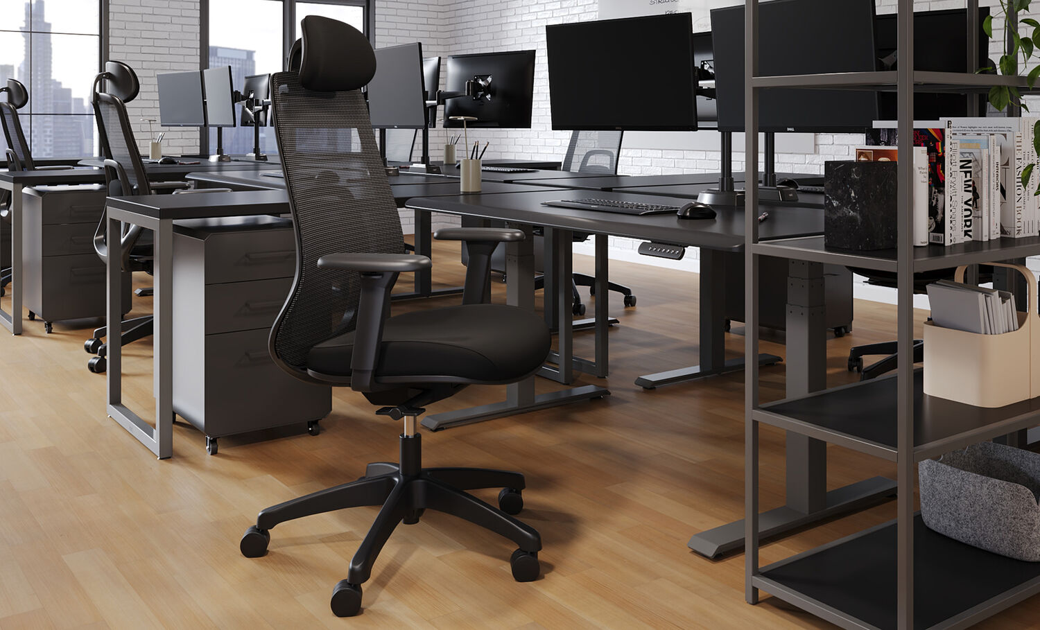 Black mesh task chair with adjustable headrest and armrests in an open office featuring standing desks, monitors, filing cabinets, and a shelving unit with books and storage bins.
