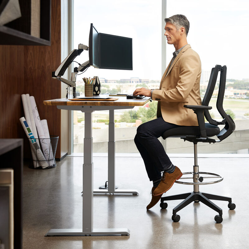 professional sitting at an Electric Standing Desk 60x30 light wood in raised position image number null
