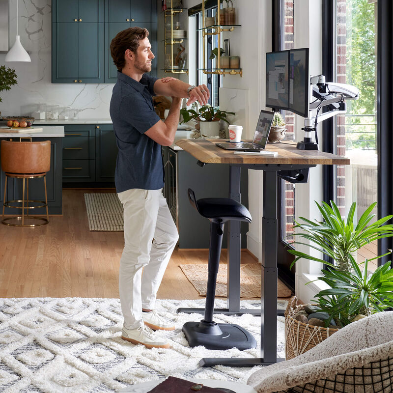 active seat placed under an electric standing desk when not in use in a home office setting  image number null