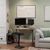 reclaimed wood standing desk lowered in a stylish home office nook with a monitor, keyboard, and ergonomic stool.