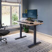 electric standing desk with comfortedge in 48x30 light wood top and black legs in raised position at home