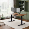 solid wood electric standing desk with a heritage walnut top with black legs in an open home office in lowered position