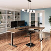 walnut finish l shape electric standing desk in a raised position in the corner of a workspace