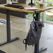 desk hook holding a filled backpack on the edge of an electric standing desk