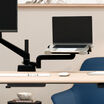 laptop sitting on top of the laptop holder installed on a desk