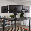 close up of the back of the triple monitor arms with three monitors setup on a vari l shape desk