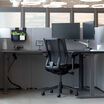 black finish l shape electric standing desk in an office workspace