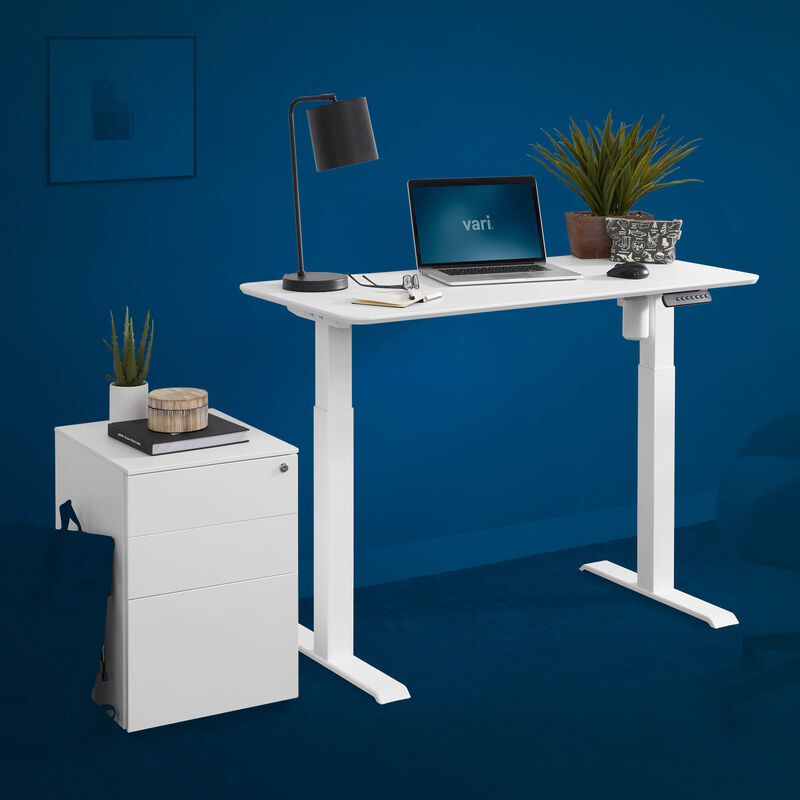 Essential electric standing desk 48 by 24 and an essential file cabinet in white are shown on a blue background image number null