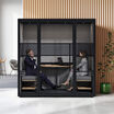 two person privacy booth in the black finish against a wall in an office with two individuals sitting and working inside