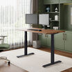 solid wood electric standing desk with a heritage walnut top with black legs in an open home office in raised position