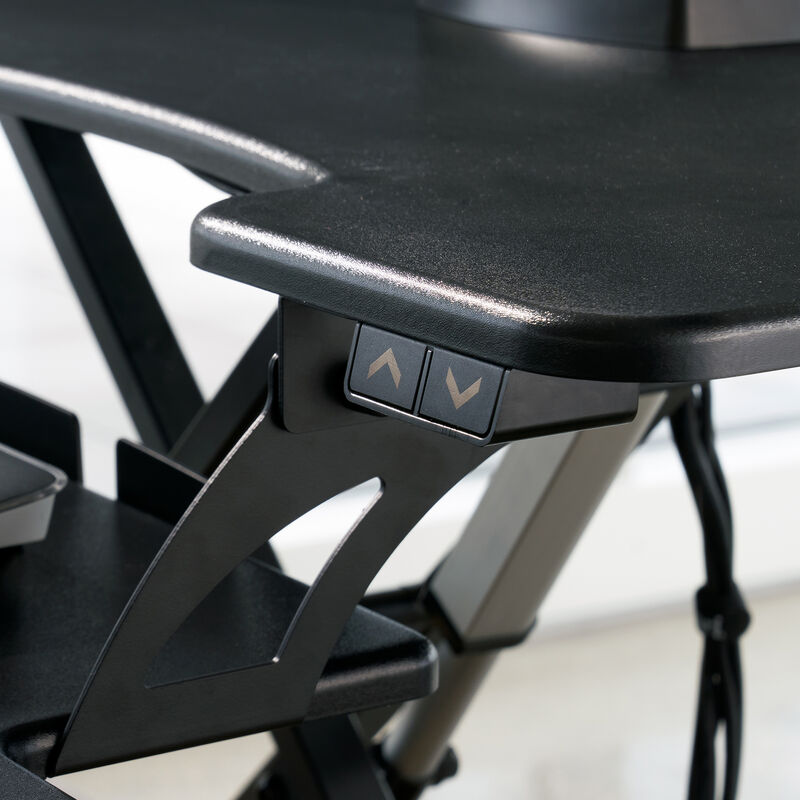Close-up of the black up and down height adjustment buttons on the side of the desk converter, with the X-frame lift mechanism visible behind. image number null