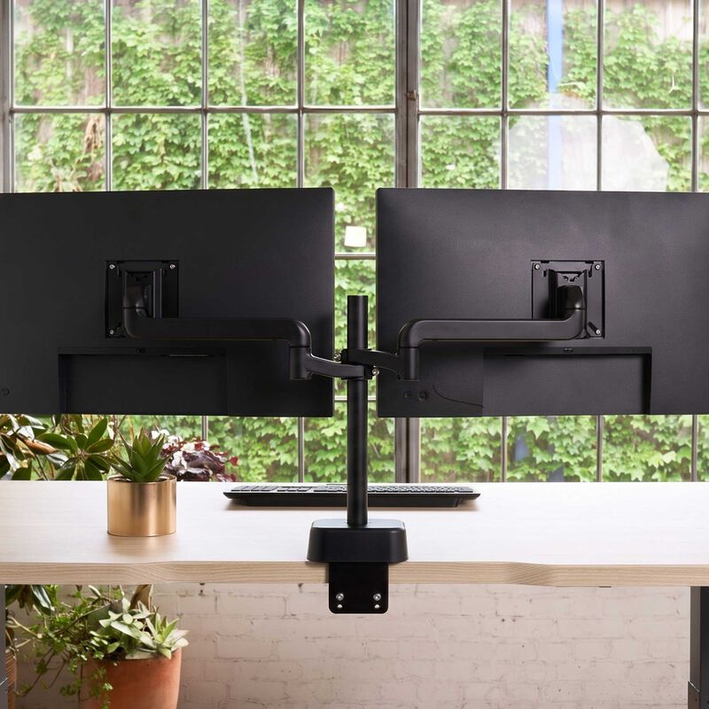 Dual monitor arm mounted to a desk holding two black monitors side by side, with a desk clamp base, in a home office with a picture frame, keyboard, and mouse. image number null