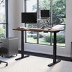 Electric Standing Desk 60x30 walnut with black legs in raised position at home