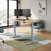 solid wood electric standing desk with a white oak top with silver legs in an open home office in raised position