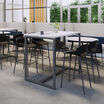 standing work table in white finish setup in an open meeting environment with four tall chairs