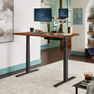 Electric Standing Desk 60x30 Dark Wood in raised position at home