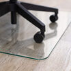 close up of the tapered edge of glass chair mat with a rolling desk chair 