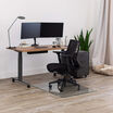 glass chair mat setup under a chair and electric standing desk on wood floor