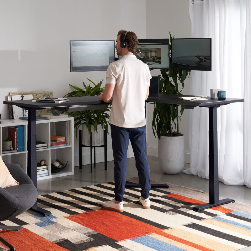 black finish l shape electric standing desk in a raised position in the corner of a workspace image number null
