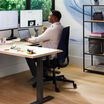 professional sitting at desk with deep blue temper-pedic chair in a home office setting