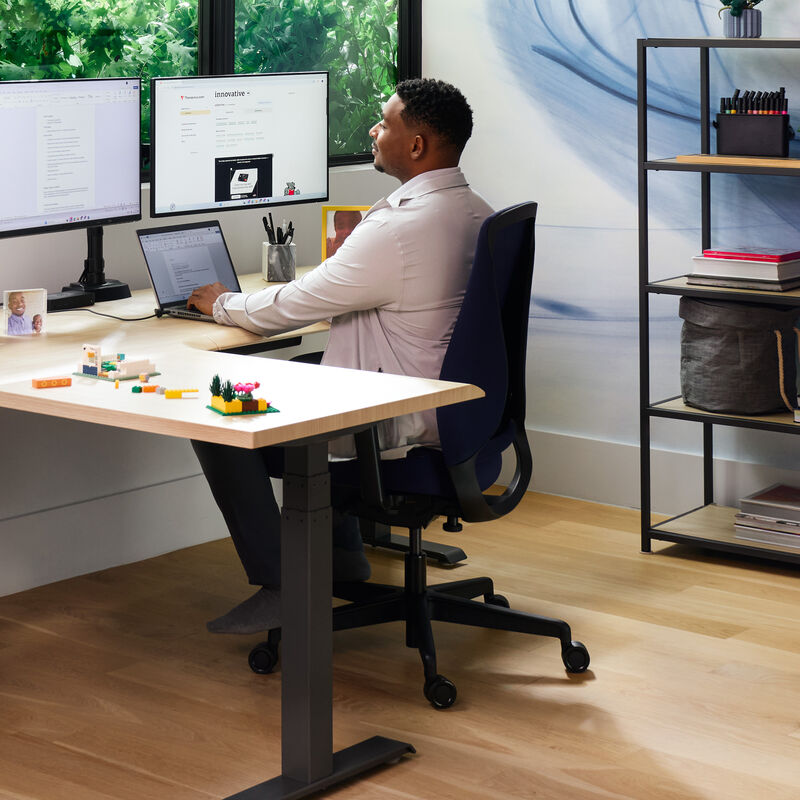 professional sitting at desk with deep blue temper-pedic chair in a home office setting image number null