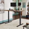 Electric Standing Desk 60x30 in reclaimed wood finish in raised position in an home office setting.