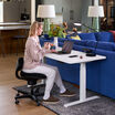 woman sitting at a desk, working on a laptop while holding a mug sitting on the core chair