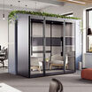 two person privacy booth in the black finish against a wall in an office with furniture inside of it angled view