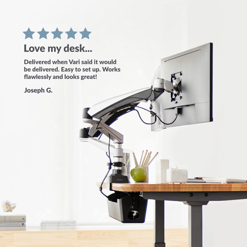 electric standing desk in an office setting with a customer review rating saying love my desk delivered when vari said it would be delivered easy to setup works flawlessly and looks great by joseph  image number null