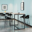 standing work table in light wood finish setup in an open meeting environment with four tall chairs