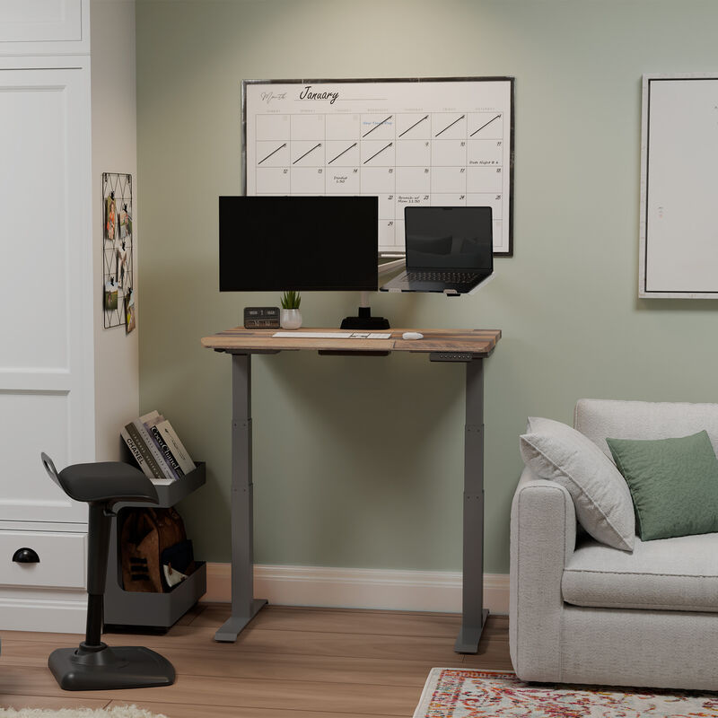 reclaimed wood electric standing desk raised in a stylish home office nook with a monitor, keyboard, and active seat image number null