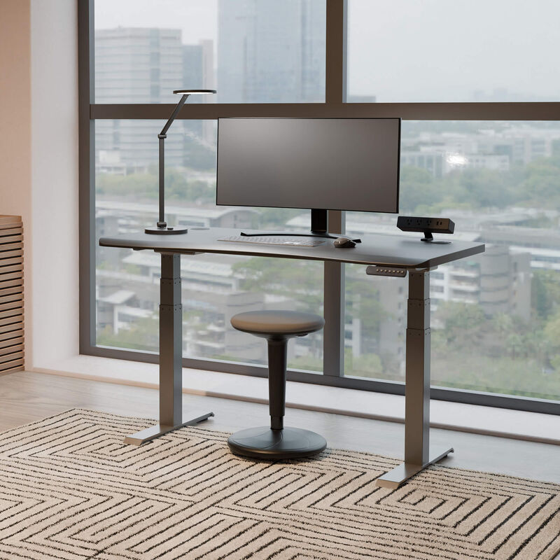 balance stool sitting in front of an electric standing desk in a office in a lowered position image number null